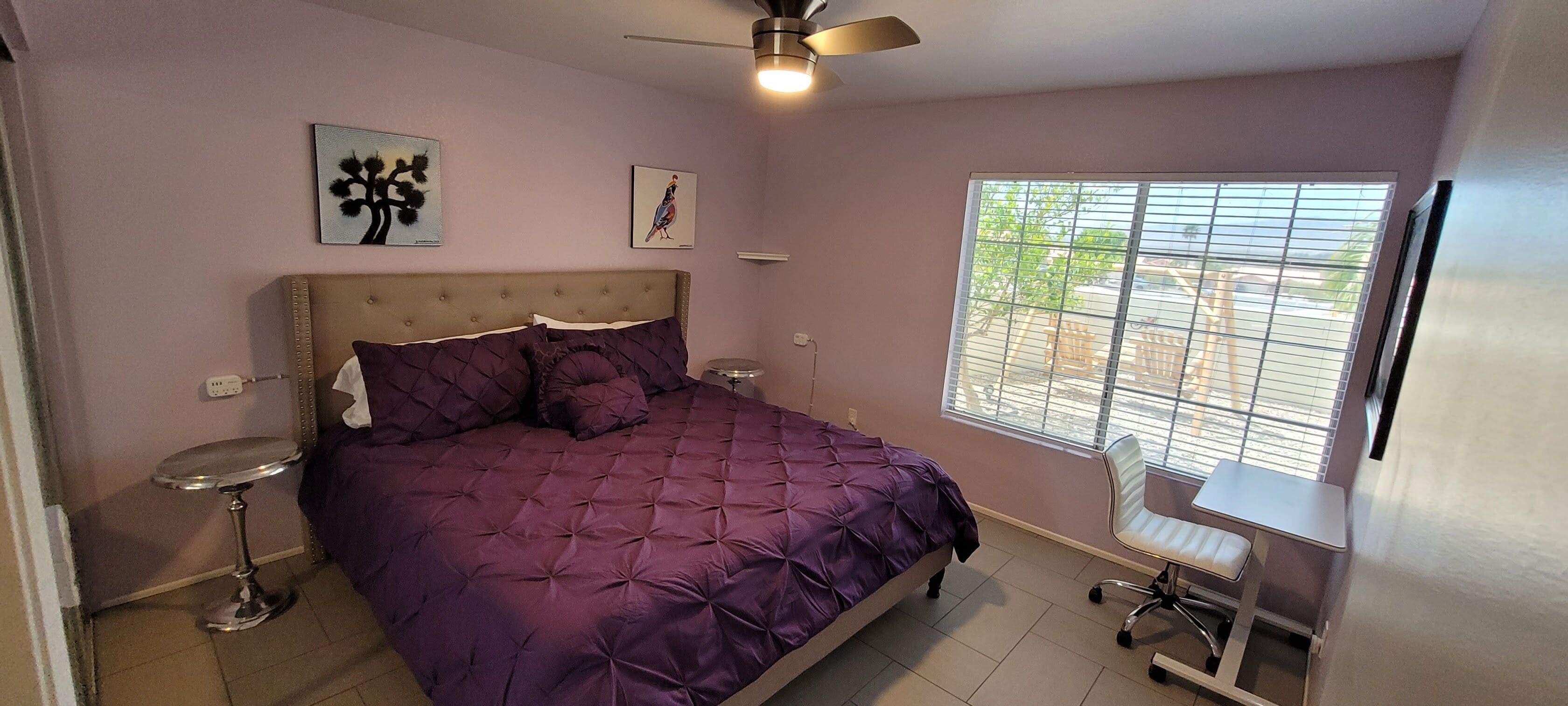 A bedroom with a bed, bedside tables, a ceiling fan, and a window with blinds.