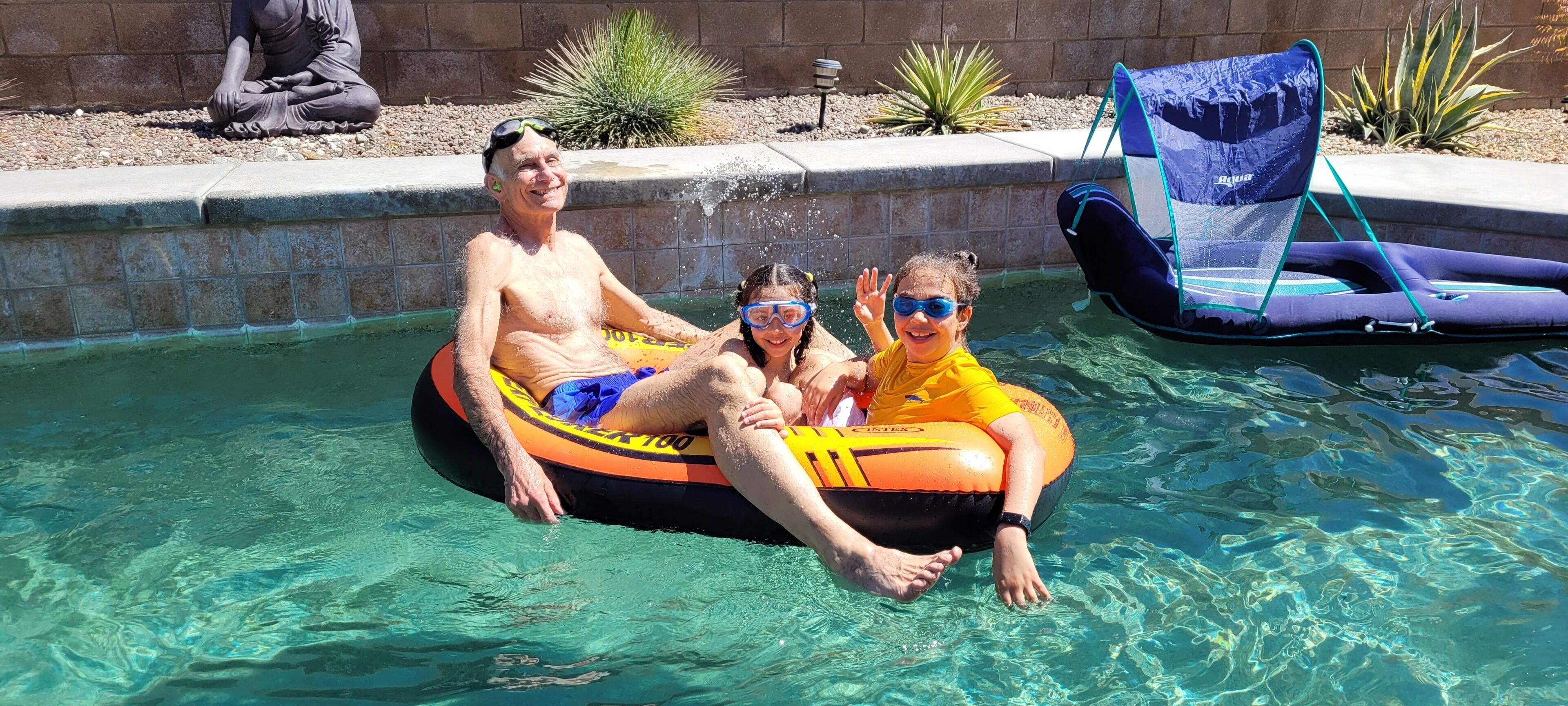 A man and a child in a pool using an inflatable raft.