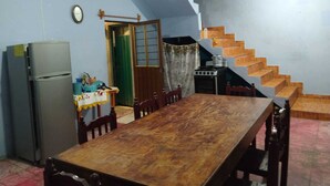 A dining area with a wooden table and chairs, a refrigerator, a stove, and a staircase leading to an upper level. - Aquetzali kin Private House with Pool (Cuautla)