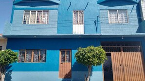 A two-story building with a blue exterior, a wooden door, and a small tree in front. - Aquetzali kin Private House with Pool (Cuautla)