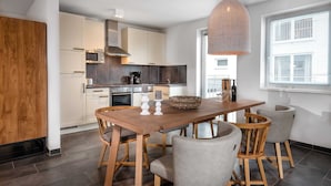 Une cuisine moderne avec des carreaux de couleur sombre, des armoires en bois et un coin repas comprenant une table et des chaises en bois.