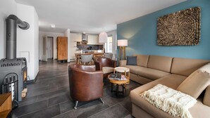 Un salon moderne avec un canapé, des fauteuils, une table et une cheminée.