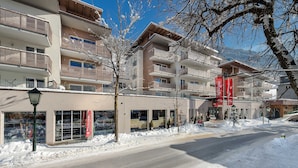 Un immeuble à plusieurs étages doté de balcons, une rue au premier plan et de la neige au sol.