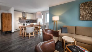 Un salon moderne comprenant un canapé, des fauteuils, une table basse et un coin repas avec une table et des chaises.