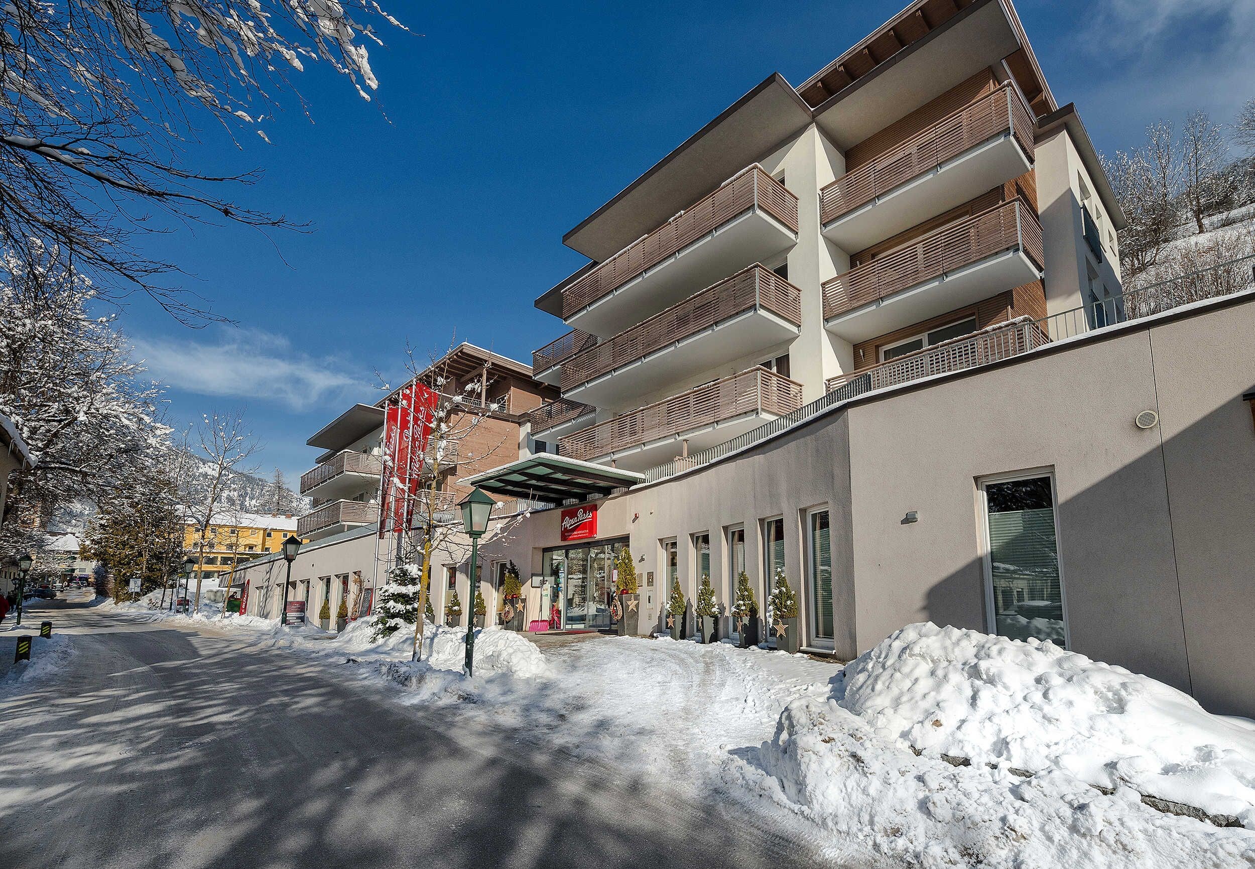 Un immeuble à plusieurs étages doté de balcons, une rue enneigée et un ciel dégagé.