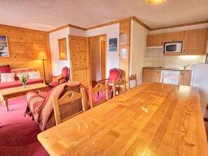 Cozy room with a large dining table and comfortable seating for four, a sofa, coffee table, and kitchen area.
