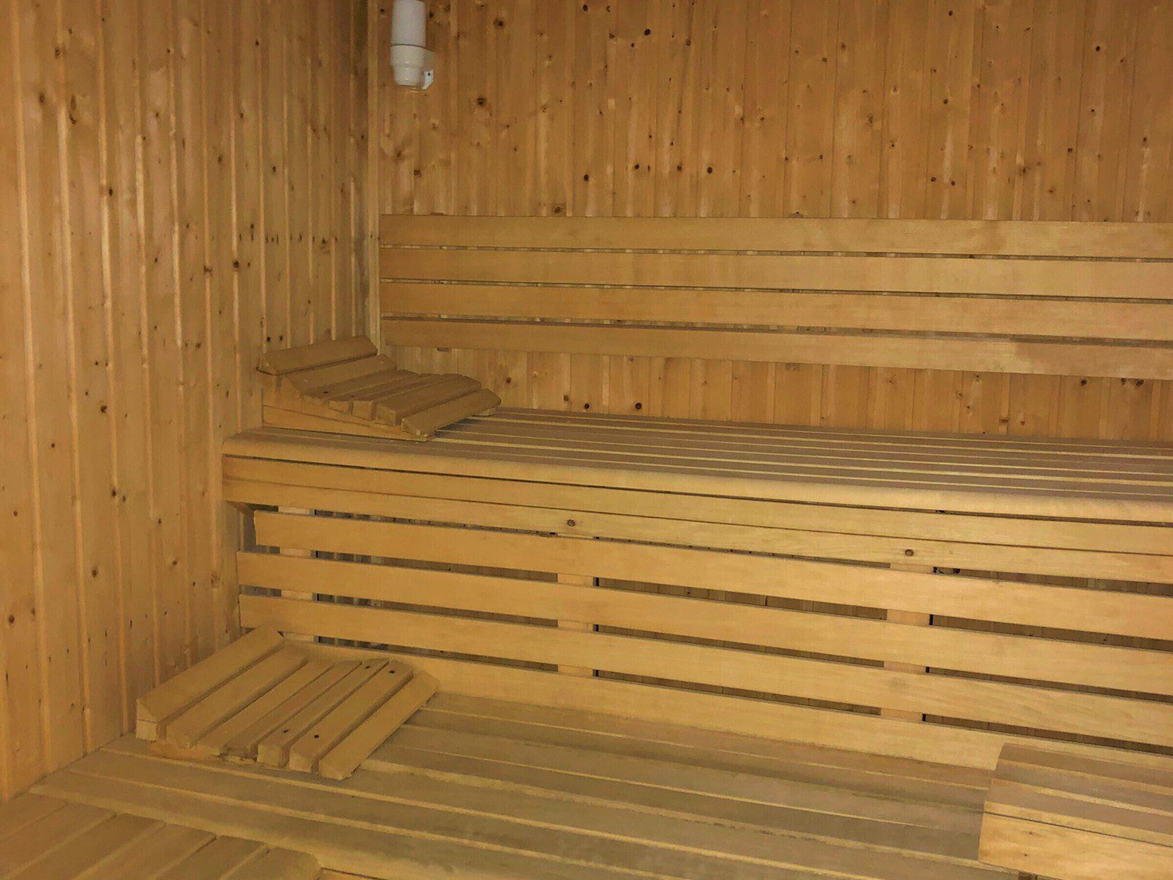 Een houten sauna met banken en een lange zitting.