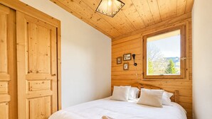 A wooden room with a bed, a window with a view, and a door. - Charming apartment with Mont Charvin view and parking (Notre-Dame-de-Bellecombe)