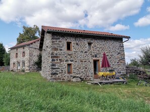 Un edificio de piedra con techo de tejas rojas, una puerta pequeña y un ventanal.