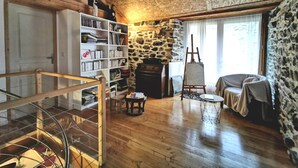 Une pièce rustique avec un mur en pierre, des étagères en bois, une cheminée et une table ronde.