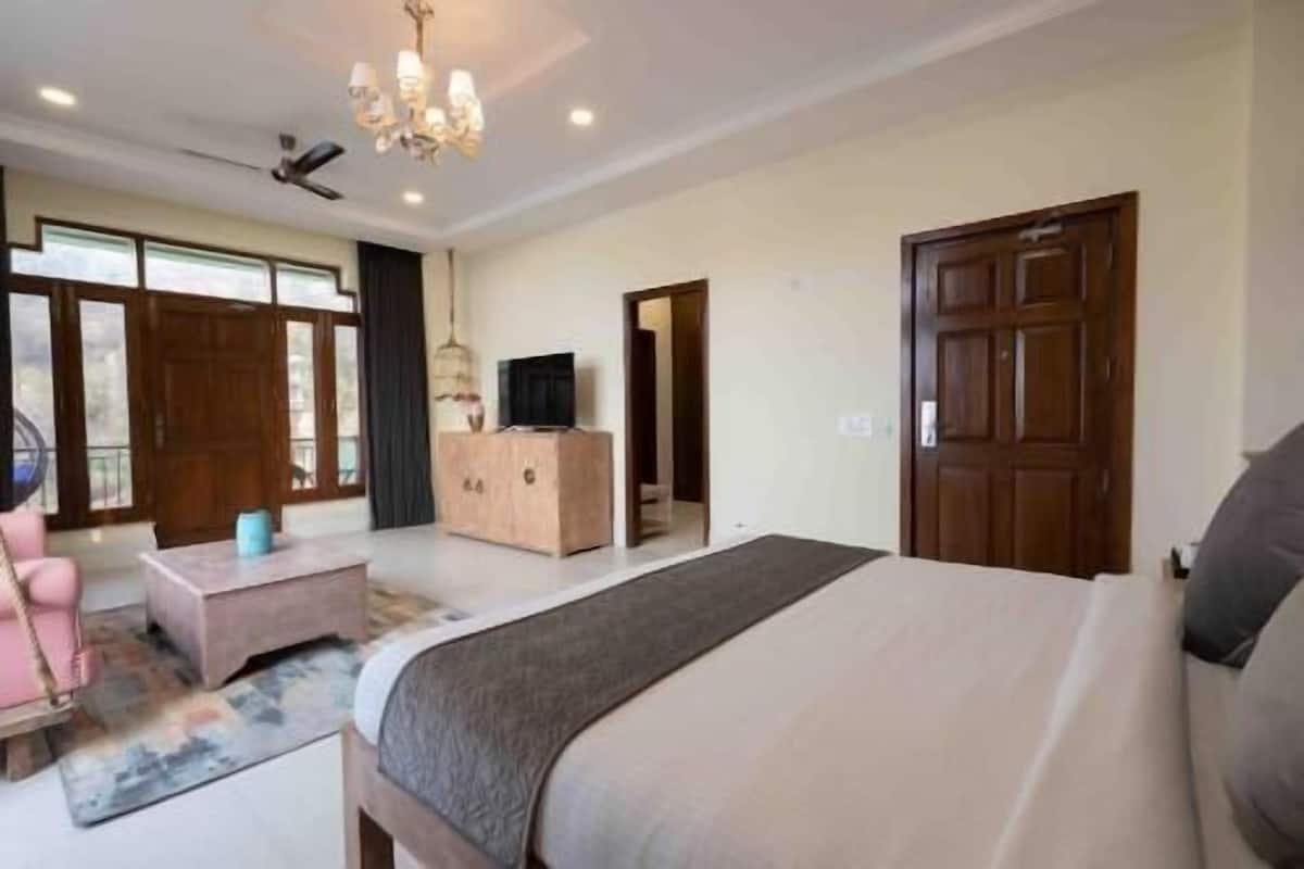 A hotel room with a bed, a TV, a wooden dresser, and a balcony.