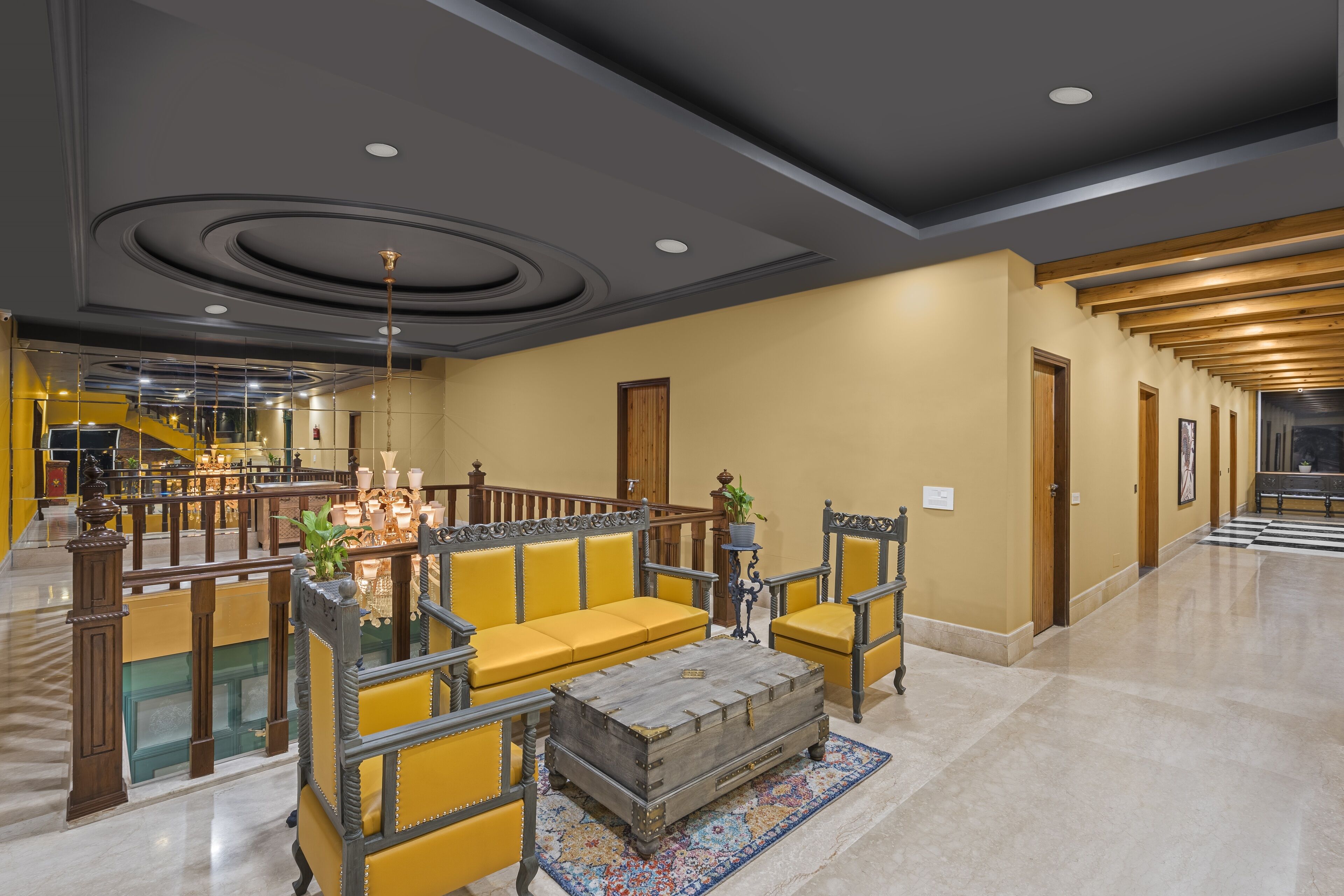 A spacious lobby with a yellow sofa set, a wooden chest, and a patterned rug.