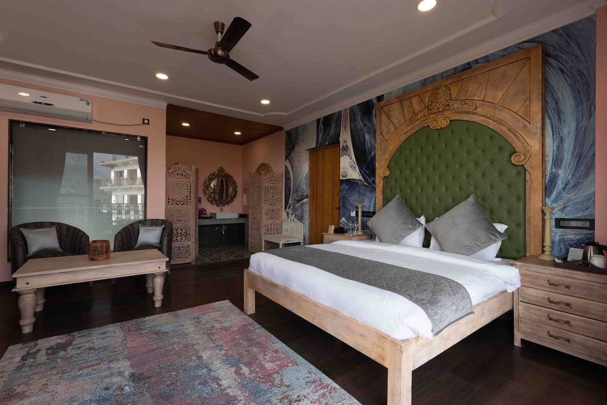 A bedroom with a bed, a nightstand, a dresser, a ceiling fan, and a large mirror.