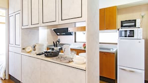 A modern kitchen with white cabinets, a microwave, a stove, and a refrigerator. - HARMONIA Tokyo Horikiri (Tokyo)