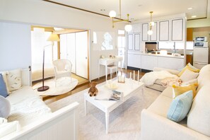 Een moderne woonkamer met een bank, een salontafel en een stoel. Achtergrond is een keukenhoek.