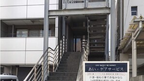 A multi-story building with a staircase leading to the entrance. There is a sign with Japanese text at the bottom of the stairs. - HARMONIA Tokyo Horikiri (Tokyo)
