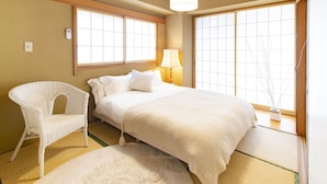 A traditional Japanese-style bedroom with tatami flooring, a white bed, a white chair, and a window with a view. - HARMONIA Tokyo Horikiri (Tokyo)