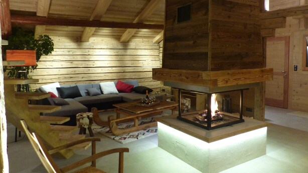 L’intérieur d’un chalet confortable, avec une cheminée, des meubles en bois et un canapé agrémenté de coussins.