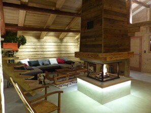 L’intérieur d’un chalet confortable, avec une cheminée, des meubles en bois et un canapé agrémenté de coussins.