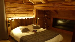 Une chambre confortable dans un chalet en bois, avec un lit, des oreillers et une échelle adossée au mur.