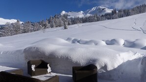Un espace extérieur enneigé avec deux chaises en osier et un monticule de neige.