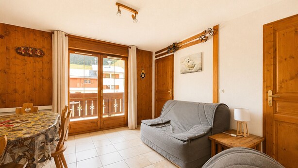 Una habitación con una mesa de comedor, sillas, un sofá, una mesita de noche y una lámpara.