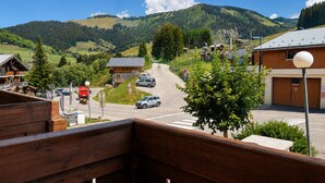 Vista de la montaña con un camino que lleva a un edificio de techo inclinado.