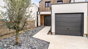 Ein modernes Haus mit Garage, einer Holzfassade und einem Kiesweg.