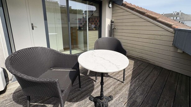 A balcony with wicker chairs and a marble table, a sliding glass door, and a view of the neighborhood. - Cozy 3-Level House in La Baule, 2 Terraces, Near Beach & Shops, Sleeps 6 (La Baule)