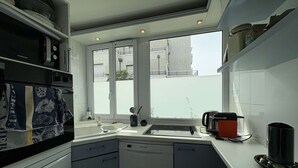 A compact kitchen with a dishwasher, a stove, and a window providing a view of the outside. - Cozy 3-Level House in La Baule, 2 Terraces, Near Beach & Shops, Sleeps 6 (La Baule)