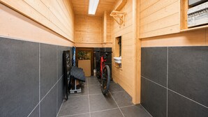 En smal hall med träväggar och ett klinkergolv, som leder in till ett rum med en cykel och ett litet fönster.