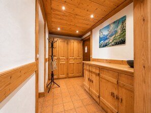A hallway with wooden cabinets, a coat rack, and a painting on the wall. - Charming apartment in the center, near the slopes (Crest-Voland)