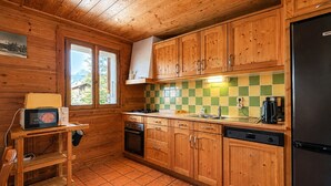Cozinha com armários de madeira, painel de azulejos, fogão e geladeira.