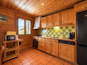 Een keuken met houten kastjes, een betegelde spatwand, een fornuis en een koelkast.