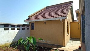 A small, single-story building with a red-tiled roof and a yellow exterior wall. - Cosmos Haven Studio (Kisumu)