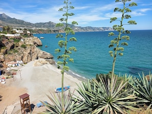 Un paysage côtier avec une plage, des falaises rocheuses et une vue dégagée sur la mer.