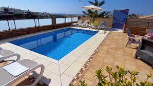 A rooftop pool with clear blue water, surrounded by lounge chairs and a tiled deck. - Villa Las Tres J (Torrox Costa)