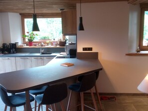 Une cuisine moderne dotée d’un long plan de travail, de meubles en bois et d’une fenêtre donnant sur un paysage verdoyant.