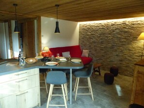 A dining area with a stone wall, wooden ceiling, and a red cushioned bench.