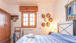 Ein Schlafzimmer mit Bett, Holzschrank, Heizkörper und einem Fenster mit Holzläden.