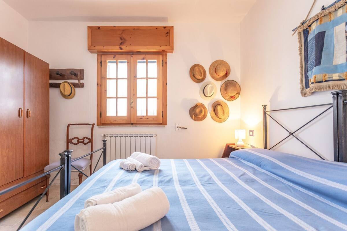 A bedroom with a bed, wooden wardrobe, radiator, and a window with wooden shutters.