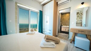 Ein modernes Hotelzimmer mit einem großen Bett, einem Badezimmer mit Steinwand und Meerblick.