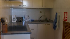 Una cucina con una macchina da caffè, un tostapane, un lavello e pensili.