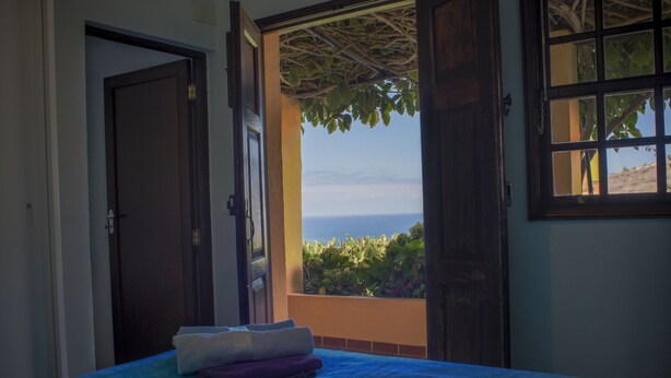Una camera da letto con un letto, una finestra vista mare e una porta.