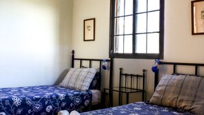 A bedroom with two single beds, a window, and a small framed picture on the wall.