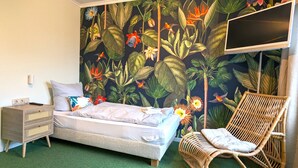 A bedroom with a bed, a nightstand, a chair, and a TV mounted on the wall. - Lieblingsplatz Hotel Wannerhus (Groemitz)