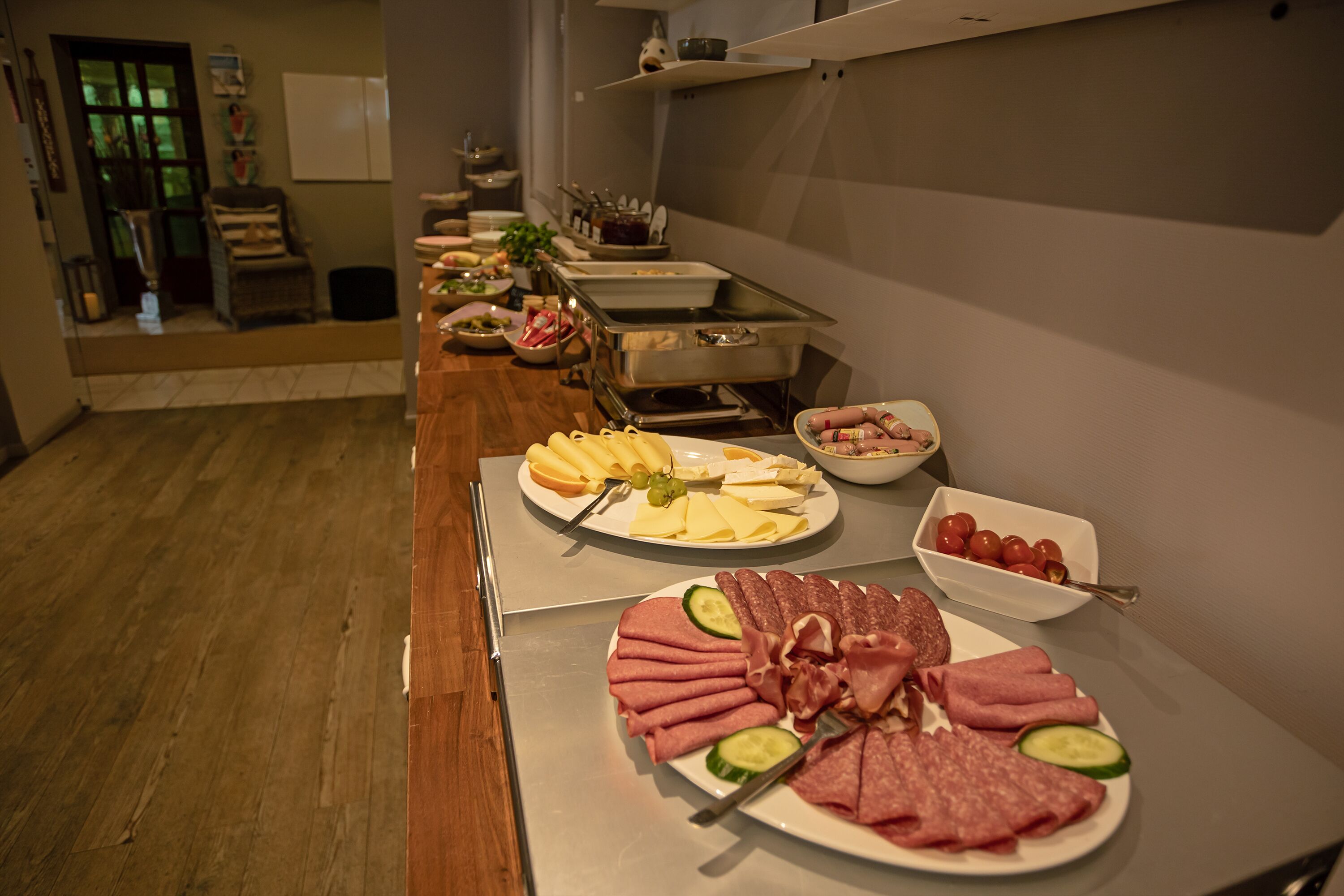 A buffet setup with various food items including meats, cheeses, and vegetables.
