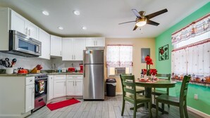 A kitchen with white cabinets, a stainless steel refrigerator, a microwave, an oven, and a ceiling fan. - Small 2BR / Fully Equipped Kitchen / Parking (Fort Lauderdale)