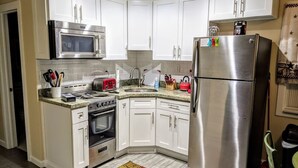 A kitchen with white cabinets, a stainless steel refrigerator, a microwave, a stove, and a sink. - Small 2BR / Fully Equipped Kitchen / Parking (Fort Lauderdale)