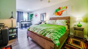 Ein Schlafzimmer mit Bett, Schreibtisch, Stuhl, Deckenventilator und einer grünen Wand.
